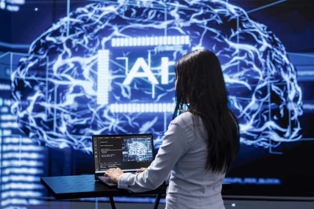 A woman at her computer analyzes a giant brain symbolizing artificial intelligence, research, and technological innovation.