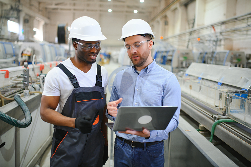 Two factory workers discussing operations in a modern manufacturing facility.
