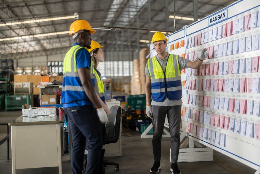 Workers reviewing a production schedule and coordinating manufacturing operations.
