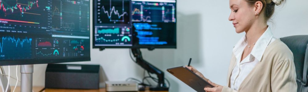 Financial,Analyst,Working,On,Multiple,Monitors,Displaying,Stock,Market,Charts,